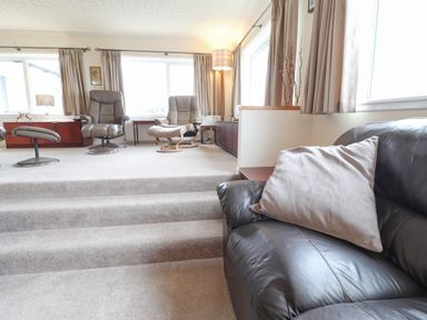 A living room with leather chairs and a sofa with a pillow at Aelwyd Y Don in Tresaith