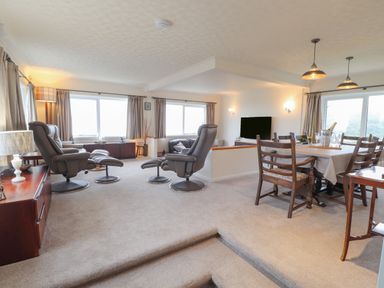 A living and dining room with recliner chairs dining table and television at Aelwyd Y Don in Tresaith