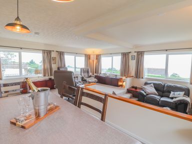 A living room with leather chairs a sofa and a dining table with champagne at Aelwyd Y Don in Tresaith