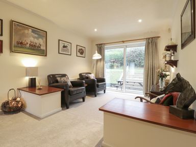 A sitting room with two leather chairs a horse sculpture and sliding glass doors at Aelwyd Y Don in Tresaith