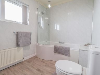 A bathroom with a bathtub shower combination and toilet at Aelwyd Y Don in Tresaith