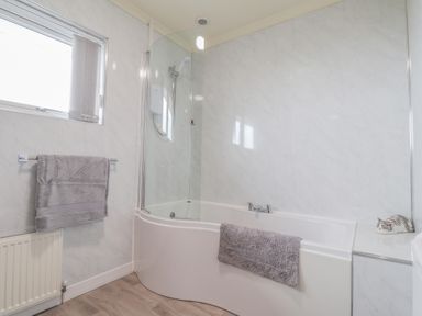 A bathroom with a bathtub shower combination towels and a small figurine at Aelwyd Y Don in Tresaith