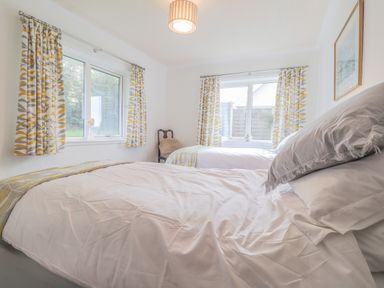 A bedroom with two single beds and patterned curtains at Aelwyd Y Don in Tresaith