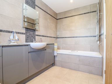 A bathroom with a sink cabinet mirror bathtub and a towel at Chy-Whel in Sticker