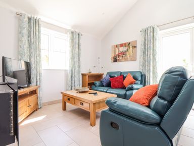 A living room with blue leather sofas and a wooden coffee table at Chy-Whel in Sticker