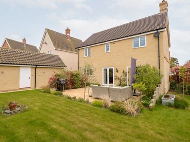 A backyard with a patio seating area a barbecue grill and grass at Coral House in Overstrand