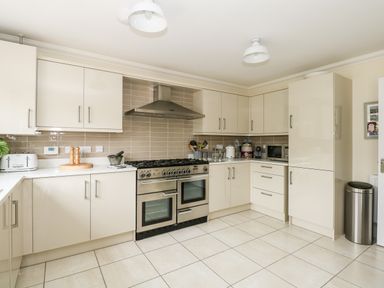 A kitchen with beige cabinets a stainless steel stove a toaster and a microwave at Coral House in Overstrand