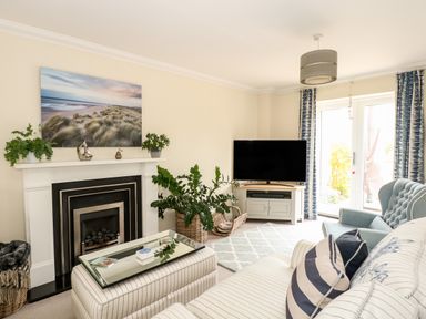 A living room with a fireplace TV armchair and sofa at Coral House in Overstrand