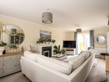 A living room with a striped sofa a television and plants at Coral House in Overstrand