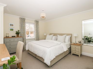 A bedroom with a bed a desk a chair a dresser a nightstand lamps plants curtains and a mirror at Coral House in Overstrand