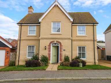 A two story brick house with a green front door and four windows with white shutters at Coral House in Overstrand