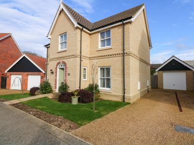 A two story house with a pitched roof a green front door and a driveway with garages at Coral House in Overstrand
