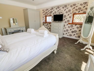 A bedroom with a bed, wardrobe, dresser, TV, and full-length mirror at Harbour Lights in Torquay
