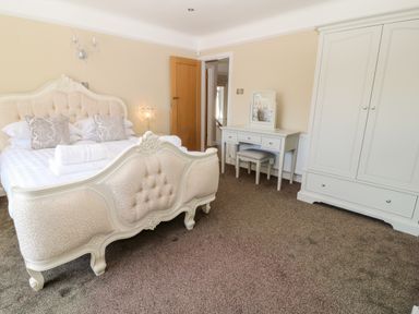 A bedroom with a double bed wardrobe dressing table and stool at Harbour Lights in Torquay