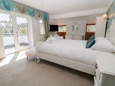 A bedroom with a white bed and rolled towels near diamond pane windows at Harbour Lights in Torquay