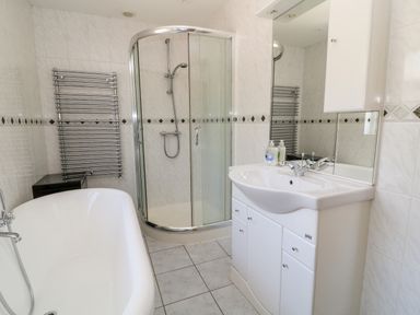 A bathroom with a bathtub shower enclosure sink with mirror and towel radiator at Harbour Lights in Torquay