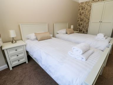 A bedroom with two single beds bedside tables lamps wardrobe and folded towels at Harbour Lights in Torquay
