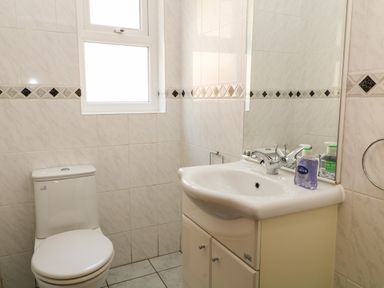 A bathroom with a toilet a sink with cabinet and a window above at Harbour Lights in Torquay