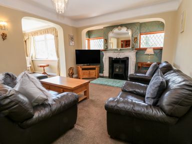 A living room with leather sofas a wooden coffee table a television and a fireplace at Harbour Lights in Torquay