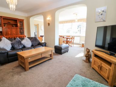 A living room with a sofa and coffee table next to a TV on a wooden stand at Harbour Lights in Torquay