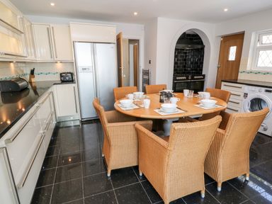 A kitchen with a round dining table set with dishes and wicker chairs at Harbour Lights in Torquay