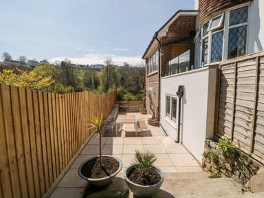 A patio area with potted plants and outdoor furniture next to a house with wooden fencing at Harbour Lights in Torquay
