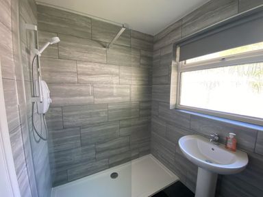 A bathroom with a walk-in shower and pedestal sink near a window at Lands End in Liskeard near St Cleer