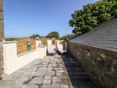 A patio area with two lounge chairs and a small table between them at Bwthyn Siop Pencaerau in Rhiw near Aberdaron