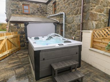An outdoor hot tub with steps next to a stone building at Bwthyn Siop Pencaerau in Rhiw near Aberdaron