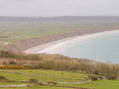 A coastline with a beach and fields separated by stone walls at Bwthyn Siop Pencaerau in Rhiw near Aberdaron