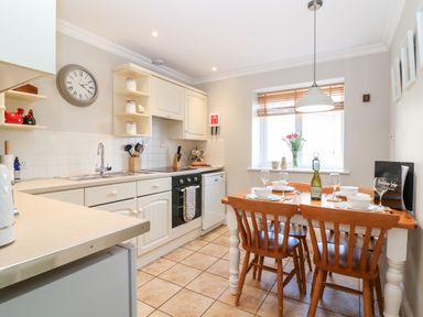 A kitchen with a dining table set for four next to a window at Farm View Lodge in Painswick