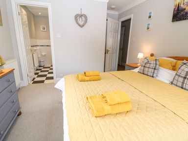 A bedroom with a bed with yellow bedding and towels and a door leading to a bathroom at Farm View Lodge in Painswick