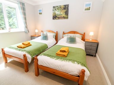 A bedroom with two single beds with green blankets and yellow towels at Farm View Lodge in Painswick