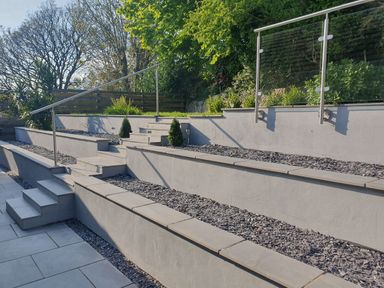 An outdoor terrace with stone steps metal railings and gravel beds with plants at Westwinds in Tenby