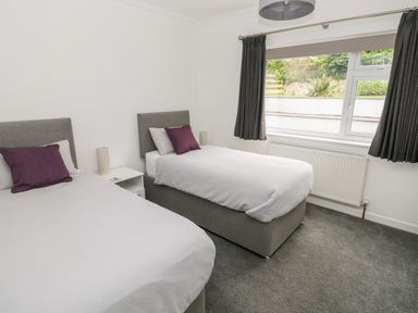 A bedroom with two single beds and a window with curtains at Westwinds in Tenby