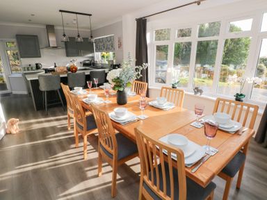 A dining room with a table set for dinner at Westwinds in Tenby