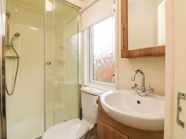 A bathroom with a shower enclosure toilet sink and a window at Exe Valley Lodge in Bampton Devon
