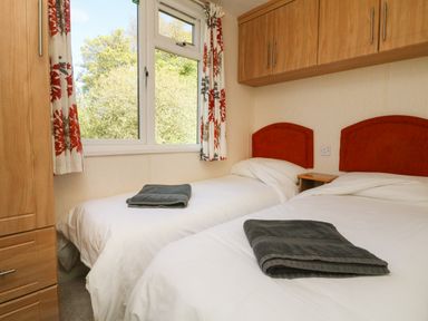 A bedroom with two single beds with white bedding and dark towels on top at Valley Lodge in Bampton Devon