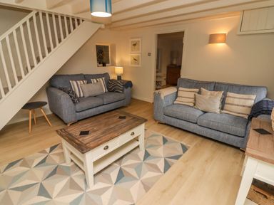 A living room with two blue sofas a wooden coffee table and a patterned rug at Sea View in Newport Pembrokeshire