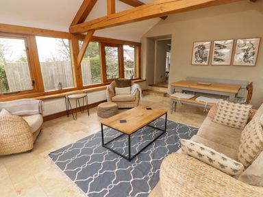A sitting room with wicker chairs a wooden coffee table and a dining table with bench seating at Sea View in Newport Pembrokeshire