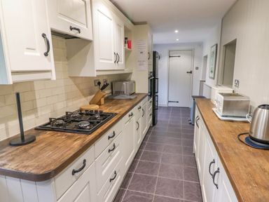 A kitchen with wooden countertops white cabinets a stove microwave toaster and kettle at Sea View in Newport Pembrokeshire