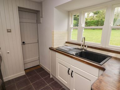A kitchen with a black sink under windows and a wooden countertop at Sea View in Newport Pembrokeshire