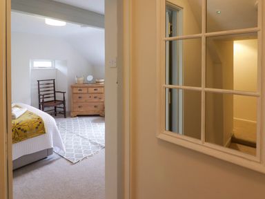 A bedroom with a bed a wooden chair a wooden dresser and a rug seen through a doorway at Sea View in Newport Pembrokeshire