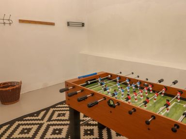 A foosball table on a patterned rug with a wicker basket and wall hooks in a room at Sea View in Newport Pembrokeshire