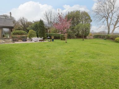 A garden with grass lawn trees patio furniture and a barbecue at Sea View in Newport Pembrokeshire
