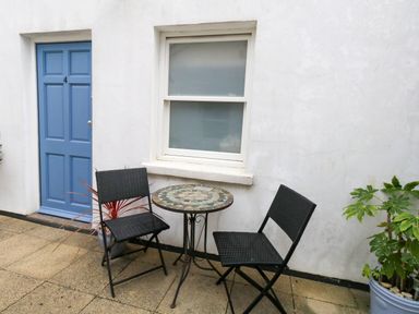 An outdoor area with a table and chairs in front of a door and window at 4 The Beaches in Weymouth