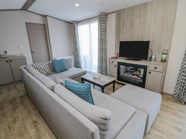 A living room with a grey sectional sofa and patterned curtains at Dreams & Streams in Bockenfield Country Park near West Thirston