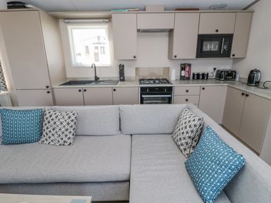 A kitchen with cabinets appliances and a gray sofa with patterned cushions at Dreams & Streams Bockenfield Country Park near West Thirston