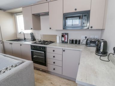 A kitchen with cabinets a sink stove oven microwave toaster kettle and canisters at Dreams & Streams in Bockenfield Country Park near West Thirston