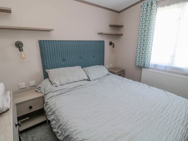 A bedroom with a double bed two bedside tables wall lamps and a window at Dreams & Streams Bockenfield Country Park near West Thirston